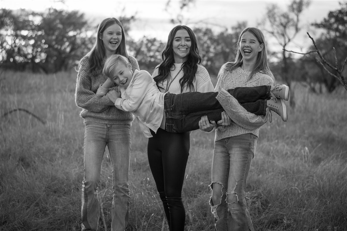 The Ahern kids laughing together outdoors in a black-and-white family portrait