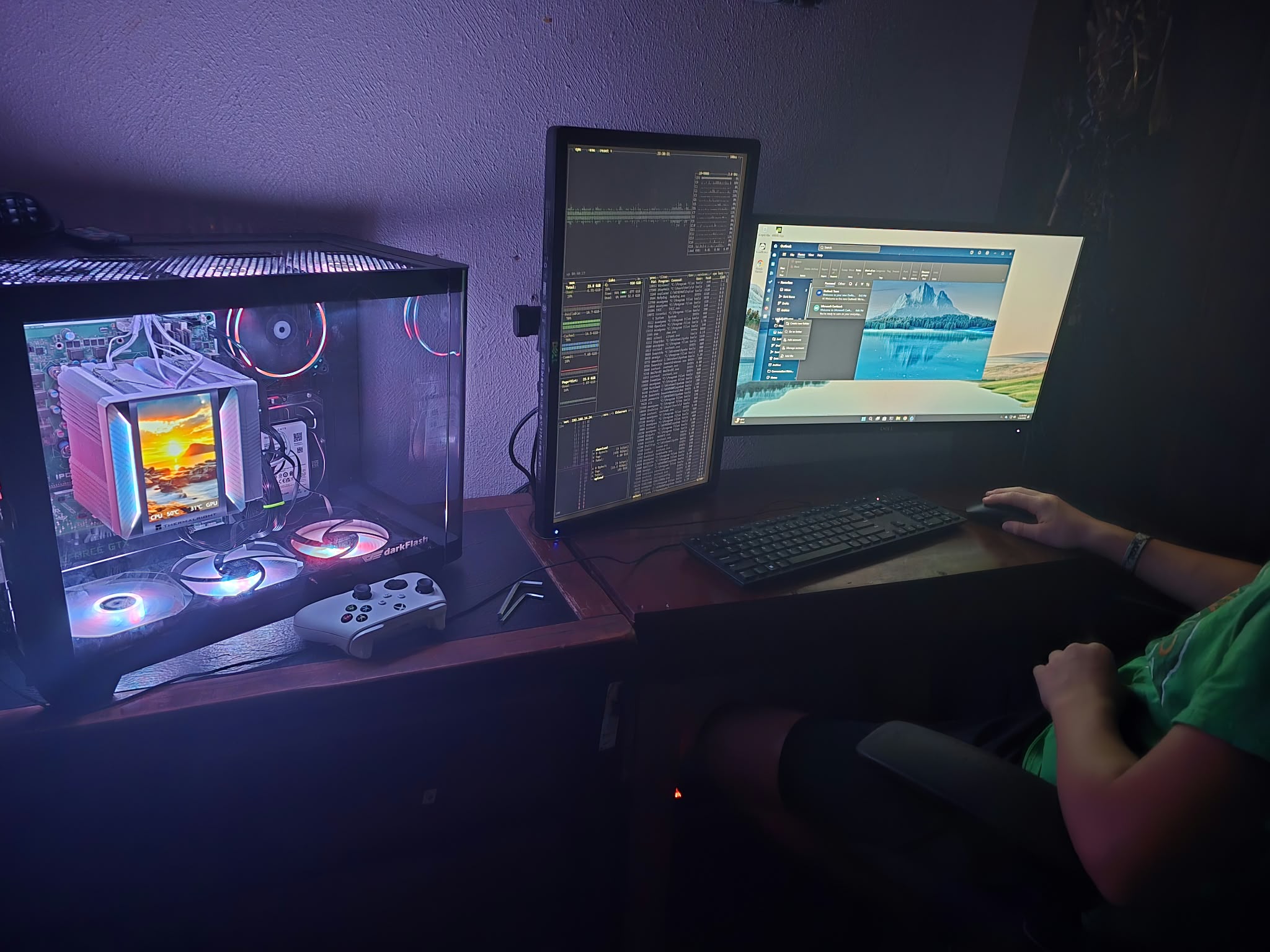 An illuminated desktop PC beside a dual-monitor setup with one screen mounted vertically