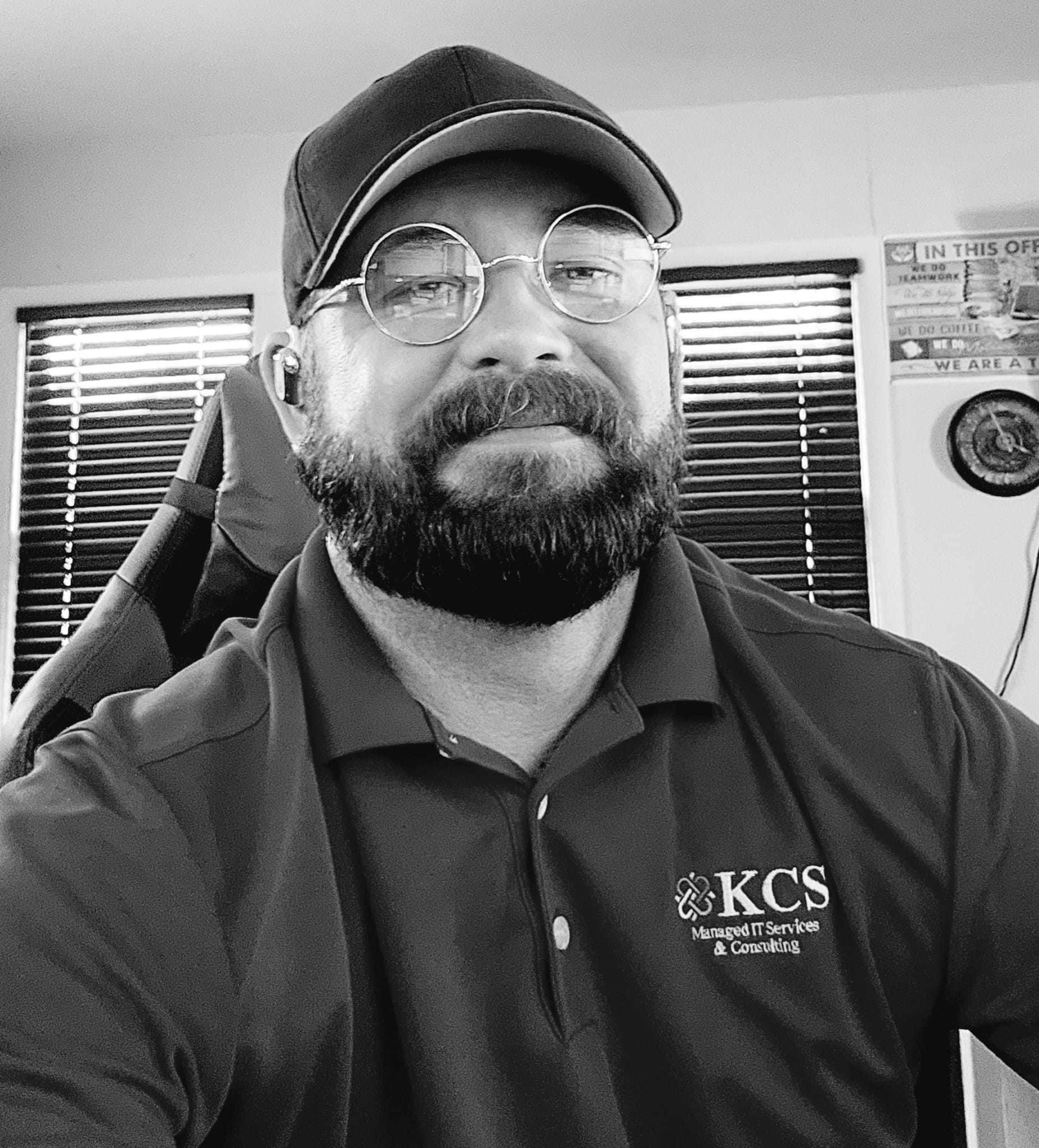 Mike Ahern wearing a cap and round glasses in his office